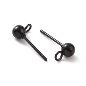 May include: Two black stud earrings. Each earring features a small, round bead at the top, connected to a straight post. One earring has a small loop attached to the bead. The earrings are set against a white background.