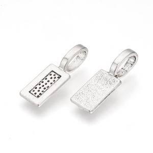 May include: Two silver-toned metal pendant charms with a rectangular shape. One charm has a textured surface and the other has a dotted pattern.