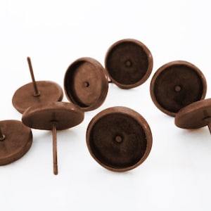 May include: Six brown metal earring settings with posts. The settings are round and have a smooth, slightly textured surface.
