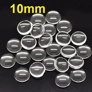 May include: A pile of 10mm clear glass cabochons, round and smooth, perfect for crafting and jewelry making.
