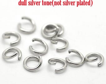 May include: A close-up of a group of silver-toned jump rings. The rings are small and have a dull finish. The text "dull silver tone (not silver plated)" is visible in the image.
