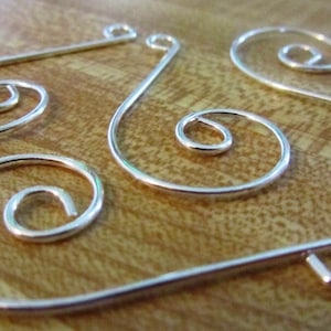 K&ouml;nnte beinhalten: Vier silberne Draht-Ornamentenaufh&auml;nger mit Spiraldesign. Die Aufh&auml;nger sind aus d&uuml;nnem Draht gefertigt und haben ein schlichtes, elegantes Design.