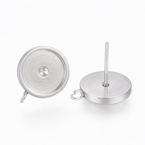 May include: A pair of silver-toned earring settings with a round bezel and a post back. The bezels are designed to hold a round cabochon.