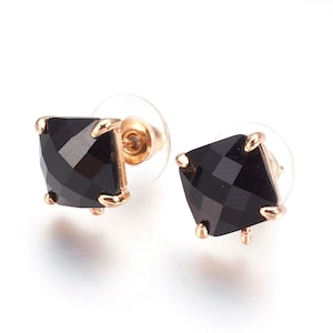 May include: A pair of gold stud earrings with black square-shaped gemstones.