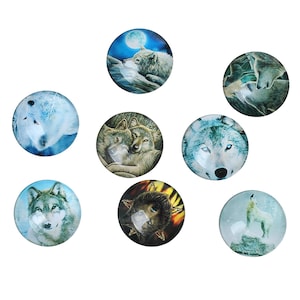 May include: A collection of eight round glass cabochons featuring wolf illustrations. The images depict wolves in various settings, including under a full moon, in pairs, and in snowy landscapes. The cabochons have a glossy finish.
