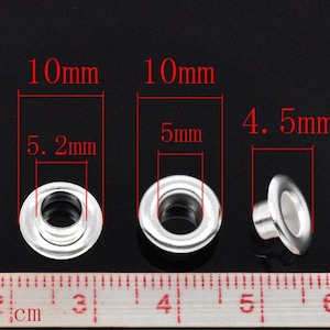 May include: Three silver metal eyelets of different sizes. The eyelets measure 10mm x 5.2mm, 10mm x 5mm, and 4.5mm x 4.5mm. A ruler is in the background.