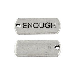 May include: Two silver-toned metal charms, one with the word "ENOUGH" engraved on it and the other blank. Both charms have a hole for attaching to a necklace or bracelet.