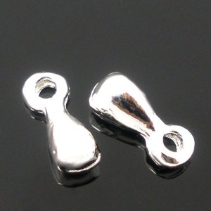 May include: Two silver-toned metal jewelry findings with a loop on each end. The findings are shaped like a teardrop with a rounded top and a pointed bottom.