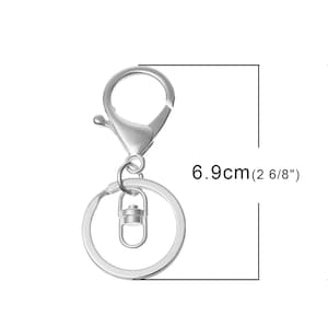 Pode incluir: Chaveiro prateado com fecho giratório e um anel com 6,9 cm de diâmetro.