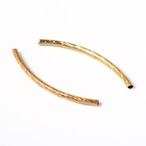 May include: Two gold-colored metal bead caps with a textured, twisted design. The caps are open at both ends.