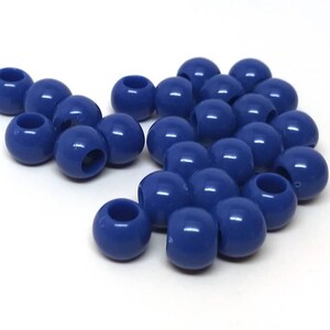 May include: A collection of navy blue, round beads with a hole through the center. The beads are smooth and shiny, and are scattered on a white surface. These beads are suitable for jewelry making and crafts.