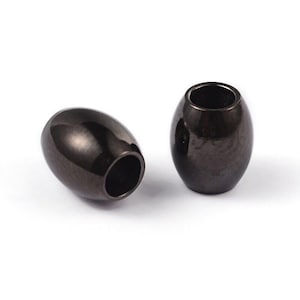 May include: Two dark gray, oval-shaped metal beads with a glossy finish. Each bead has a hole running through the center, and they are set against a white background. The beads are likely used for jewelry making or other crafts.