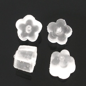 May include: Four clear plastic earring backs in the shape of a flower. The backs are designed to be used with stud earrings.