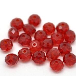 May include: A pile of red faceted glass beads. The beads are round and have a shiny finish.