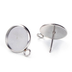 May include: A pair of silver-toned earring blanks with a round bezel setting and a loop for hanging charms. The earring posts are attached to the back of the bezels.