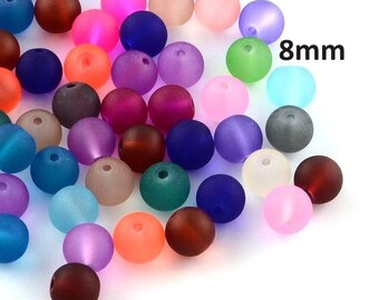 May include: A collection of colorful, round beads in various shades, including blue, pink, purple, and green. The beads are approximately 8mm in diameter. The image shows a variety of colors and textures, suitable for jewelry making or crafts.