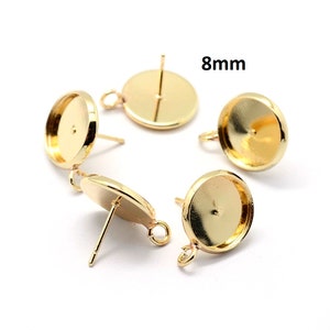 May include: Four gold-toned earring settings with 8mm round bezels. Each setting has a post and a loop for attaching a finding.