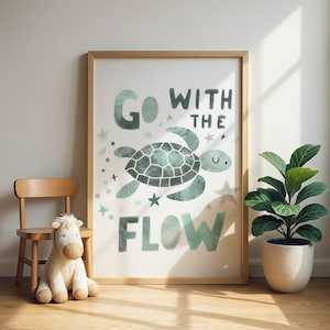 Könnte beinhalten: Ein gerahmter Kunstdruck mit einem hellen Holzrahmen. Der Druck zeigt eine Illustration einer türkisfarbenen Schildkröte mit den Worten "Go with the Flow". Sterne und andere dekorative Elemente umgeben die Schildkröte. Ein kleiner Holzstuhl und ein Stofftier befinden sich vor dem Druck.
