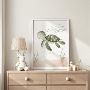 Könnte beinhalten: Ein gerahmter Aquarelldruck einer Meeresschildkröte, die unter Wasser schwimmt. Die Schildkröte ist grün und braun, mit einem hellgrünen Kopf und einem gemusterten Panzer. Der Hintergrund zeigt hellbraunen Sand und grüne Algen.