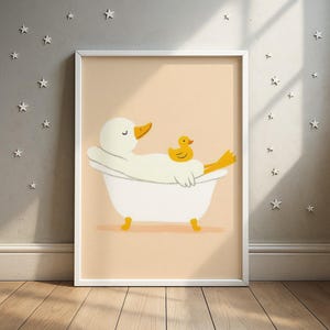 Könnte beinhalten: Gerahmte Illustration einer weißen Ente, die sich in einer weißen Badewanne mit einer gelben Quietscheente entspannt. Die Ente hat einen orangefarbenen Schnabel und gelbe Füße. Der Hintergrund ist hellpfirsichfarben mit weißen Sternen.