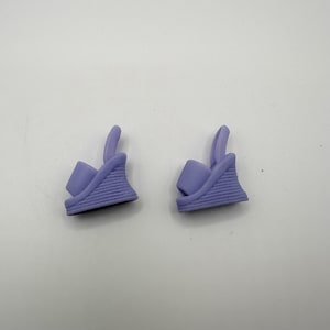 May include: Two lavender wedge sandals. Each sandal features a strap that goes around the ankle and a wedge heel with horizontal ridges. The sandals are made of a solid, smooth material.