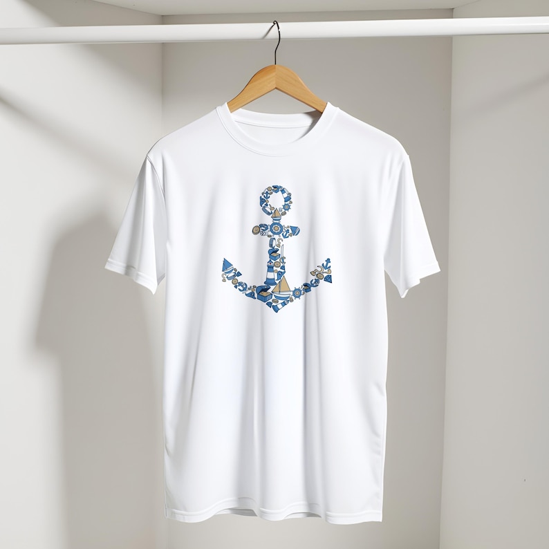 Puede incluir: Camiseta blanca con un dise&ntilde;o de ancla azul. El ancla est&aacute; compuesta por patrones n&aacute;uticos en azul y blanco. La camiseta cuelga de una percha de madera sobre un fondo blanco.