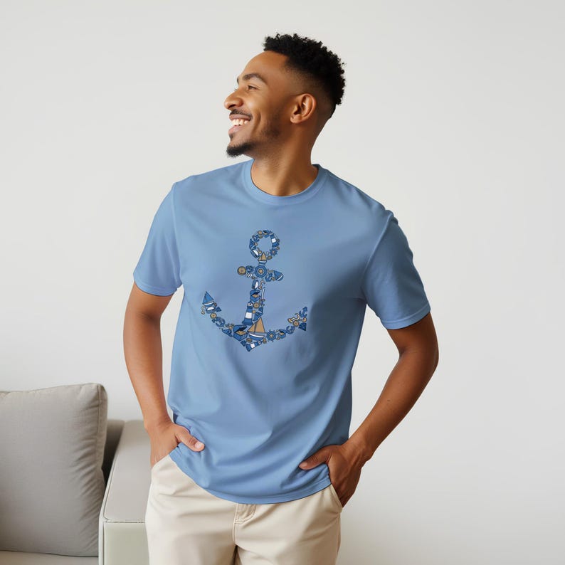 Puede incluir: Una camiseta azul claro con un dise&ntilde;o de ancla n&aacute;utica. El ancla est&aacute; compuesta por varios elementos n&aacute;uticos azules y blancos, incluyendo veleros, salvavidas y detalles de cuerda. La camiseta es de material suave y tiene mangas cortas.
