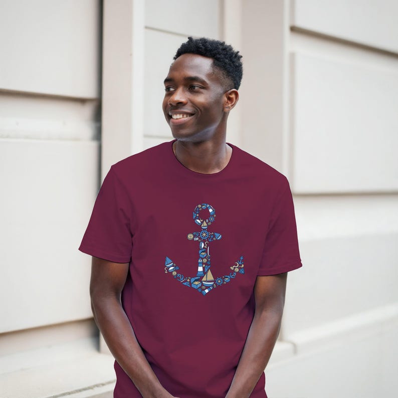 Puede incluir: Camiseta burdeos con un dise&ntilde;o de ancla n&aacute;utica. El ancla est&aacute; compuesta por varios elementos n&aacute;uticos azules y blancos, como barcos, ruedas y salvavidas. La camiseta es de color burdeos liso.