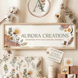 Può includere: Un'insegna rettangolare con cornice in legno che riporta il testo AURORA CREATIONS e HANDMADE WITH LOVE & NATURAL MATERIALS, accompagnata da una pochette a motivi floreali, un rocchetto di spago, perline di legno e blocchi con illustrazioni.