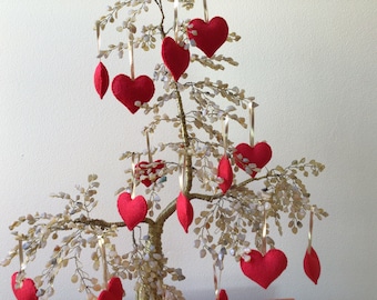 May include: A gold wire tree with red felt heart ornaments hanging from the branches.