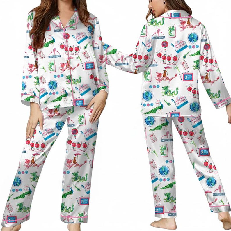 Puede incluir: Conjunto de pijama de sat&eacute;n blanco con un estampado colorido con dragones, pavos reales y otros dise&ntilde;os caprichosos. El conjunto incluye una camisa abotonada de manga larga y pantalones a juego, ribeteados con ribetes rosas.
