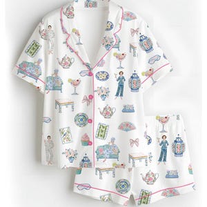 May include: A white short-sleeve pajama set with pink piping, featuring a repeating print of teapots, cocktails, decorative vases, small tables, cupcakes, fans, bows, and figures lounging on sofas, all rendered in soft pastel colors across the fabric.