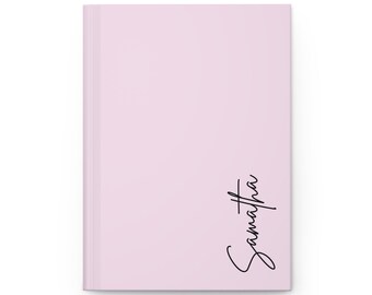 Cuaderno de tapa dura rosa mate con nombre personalizado y páginas rayadas.