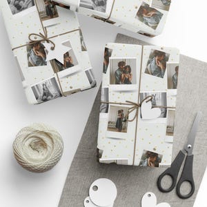 May include: Wrapped gifts featuring black and white photographs, tied with string and decorative tags. The wrapping paper is white with gold star details. A ball of twine and scissors are also present.