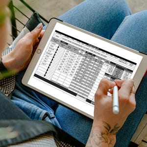 Puede incluir: Una tableta muestra un registro de navegación detallado, con columnas y filas de datos. Una persona usa un lápiz óptico. La persona lleva vaqueros azules. La pantalla es brillante.