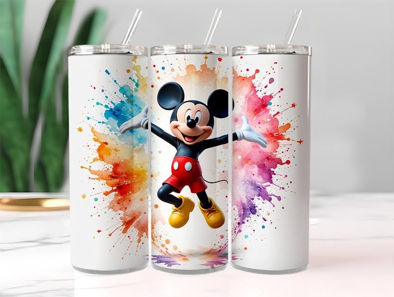 May include: White tumbler featuring Mickey Mouse with a colorful watercolor splash design. The tumbler has a silver lid and a clear straw. Mickey Mouse is wearing red shorts, yellow shoes, and white gloves.