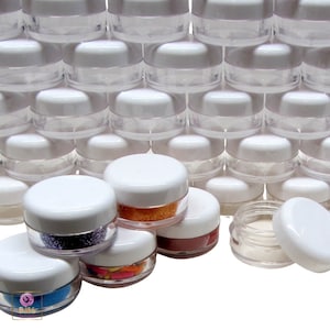 May include: A stack of clear plastic containers with white lids. The containers are filled with various colorful glitter and beads.