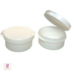 May include: Two white plastic containers with lids. The containers are round and have a smooth surface. The lids have a small lip on the edge. One container is open and the other is closed.