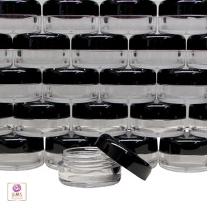 May include: A stack of 30 clear plastic jars with black lids. The jars are small and round, and they are perfect for storing small items like jewelry, beads, or other crafts.