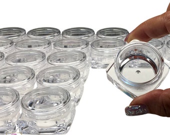 May include: A group of 20 clear plastic square containers with lids. The containers are arranged in a semi-circle with one container being held in a hand.