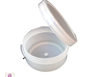 May include: A clear plastic round container with a lid. The lid is open and the container is empty.