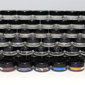 May include: A large stack of clear plastic jars with black lids. The jars are arranged in a pyramid shape. The jars are filled with various colorful items, such as glitter, beads, and candy.