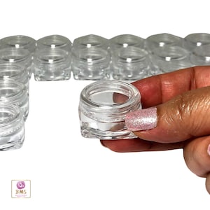 May include: A set of 12 clear plastic containers with a square base and a round lid. The containers are small and perfect for storing small items like jewelry, makeup, or craft supplies.