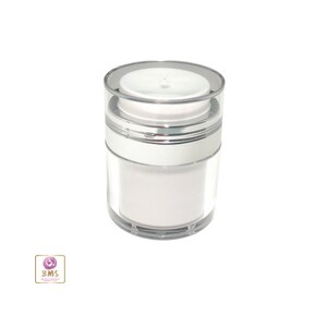 May include: A clear plastic airless pump bottle with a silver ring around the middle and a white lid. The bottle is empty.
