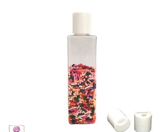 May include: A clear plastic bottle with a white cap filled with colorful sprinkles. Two additional white caps are shown next to the bottle.
