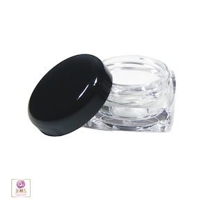 May include: A clear square plastic jar with a black lid. The jar is empty and the lid is off.