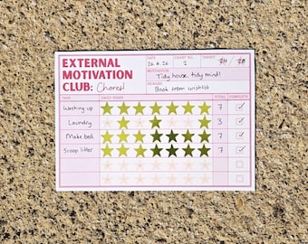 May include: A rectangular chore chart titled External Motivation Club: Chores! with pink borders and text. It features rows for tasks like Washing up, Laundry, Make bed, and Scoop litter, with gold star stickers tracking progress and handwritten notes.