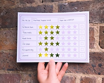 May include: A white habit tracker sheet with purple borders featuring a date field of 06.06.26, an intention of Healthier, happier mind, and a motivation of Item off wishlist. It includes six task rows with gold star icons and checkboxes.