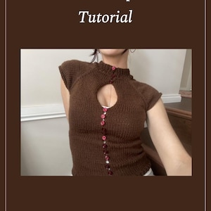 Puede incluir: Top de punto marrón con cuello de cerradura y botones rojos. El top tiene mangas cortas y cuello alto. El texto "Knitted Top 02 Tutorial" se muestra en la parte superior.