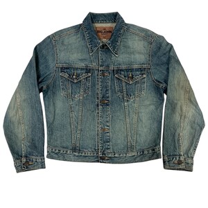 May include: A blue denim jacket with a button-up front, two chest pockets, and two side pockets. The jacket has a classic collar and long sleeves. The brand name "BIG JOHN" is visible on a label at the back of the collar.